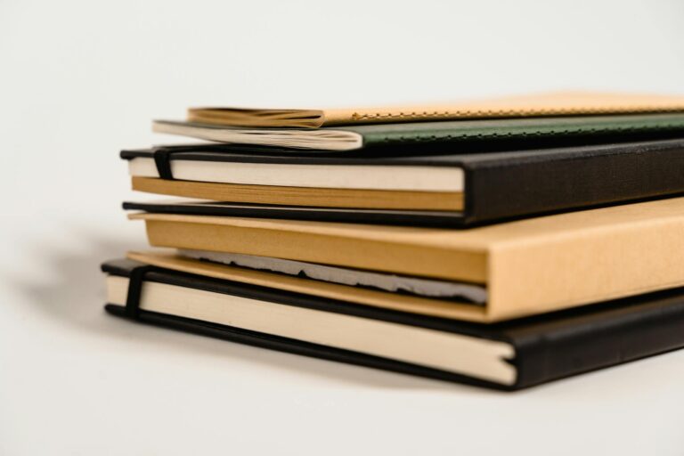 Close-up of various notebooks stacked against a white background.